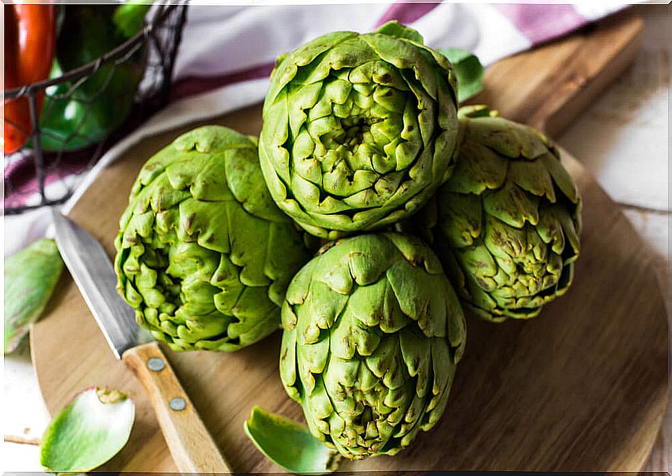 fresh artichokes on wooden board