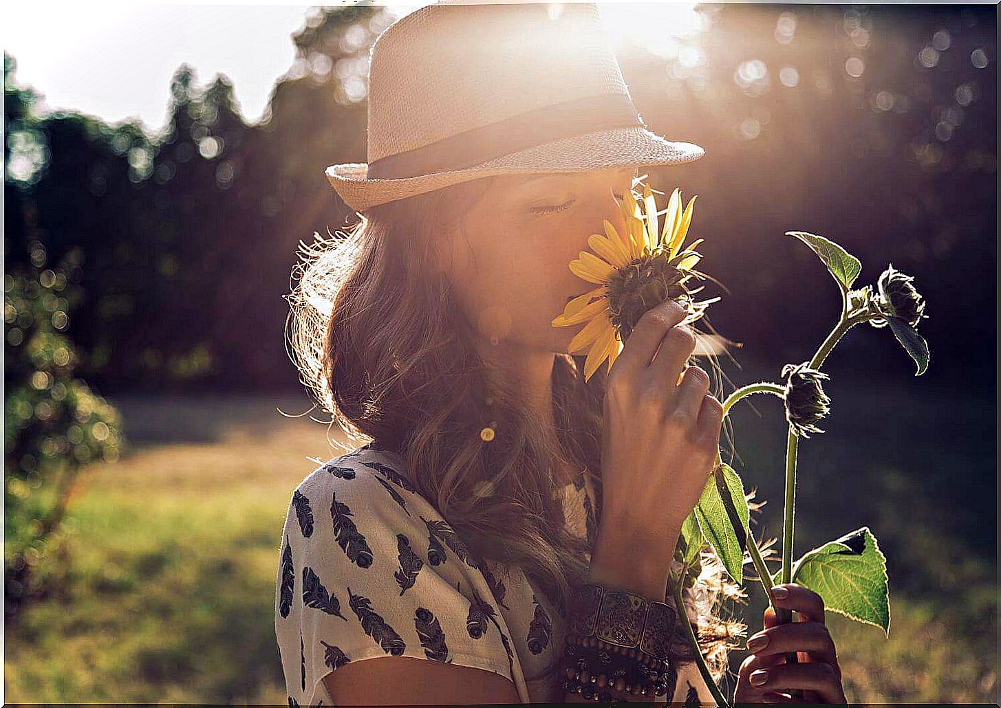 Happy woman smelling a sunflower.