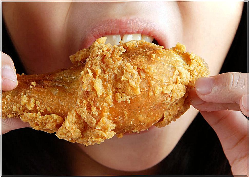 Woman eating a chicken thigh.