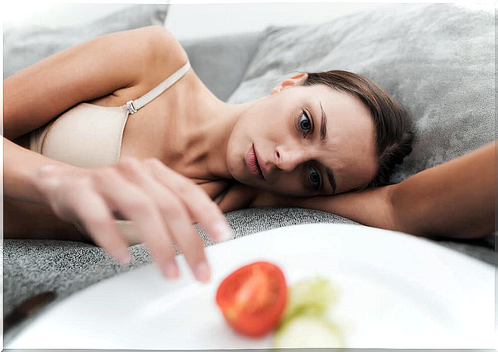 Woman with anorexia next to an almost empty plate of food.