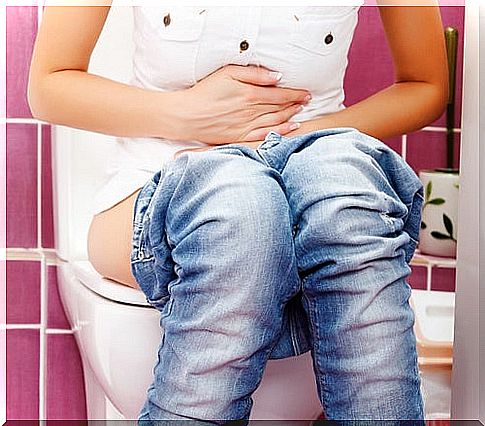 Woman sitting on toilet with hands on abdomen